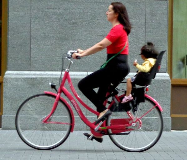 Frau auf Fahrrad mit Kind auf Kindersitz