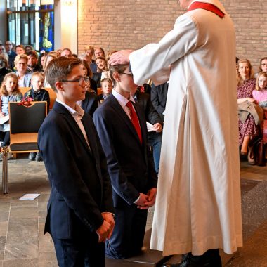 Foto von Pfarrer Kruschke, wie er zwei Konfirmanden einsegnet.