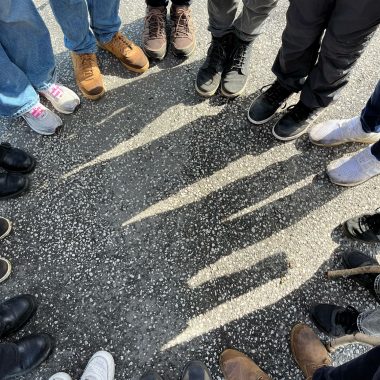 Füße in Schuhen von Menschen, die im Kreis stehen.