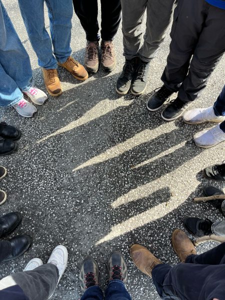 Füße in Schuhen von Menschen, die im Kreis stehen.