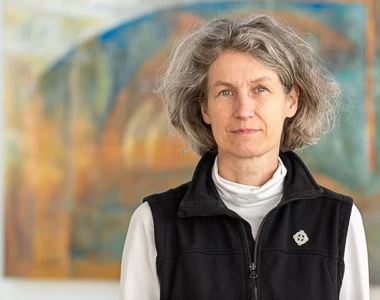 Vrouw met grijs haar en vest.